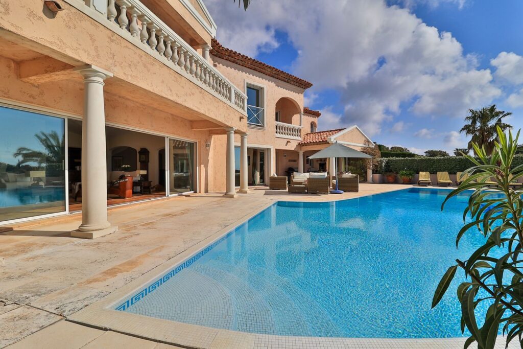 Terrasse ensoleillée avec piscine privée et transats, offrant un espace de détente avec vue dégagée.