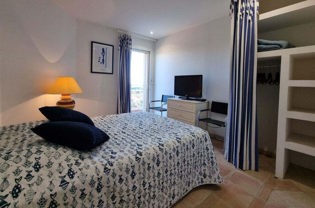 Chambre au design artistique, combinant motifs colorés, mobilier rustique et ouverture sur l’extérieur.