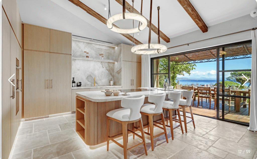 Cuisine moderne haut de gamme avec îlot central, bois clair et vue sur la terrasse de la villa