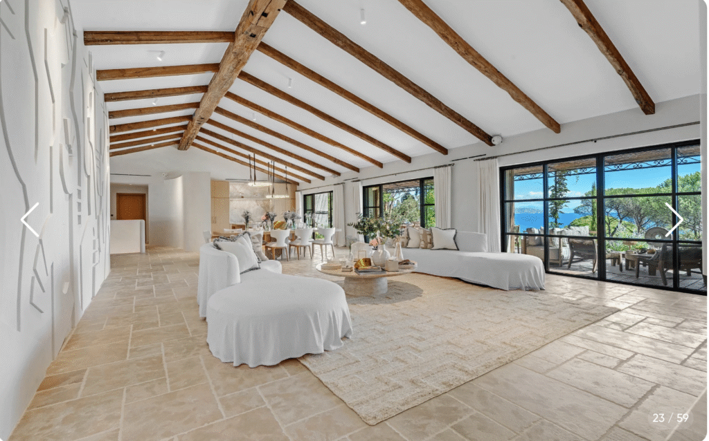 Salon principal design provençal avec poutres apparentes, cheminée et grandes baies vitrées vue mer