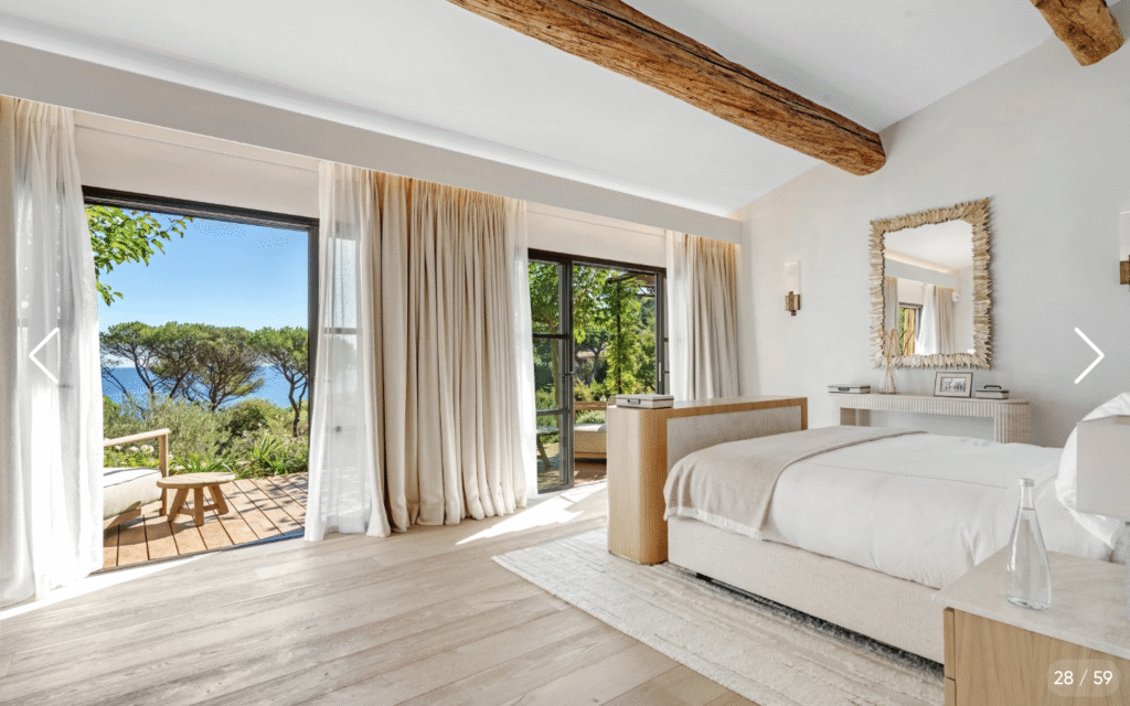 Chambre avec lit king size, décoration épurée et grandes portes fenêtres offrant une vue mer