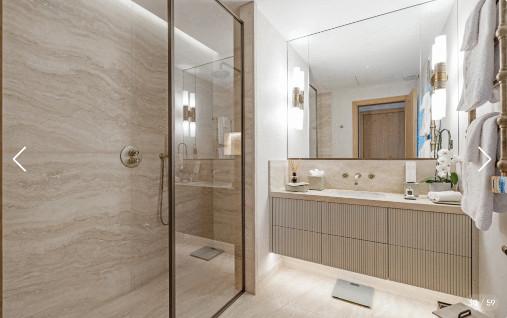 Salle de bain en marbre dans la suite principale, avec grande douche à l'italienne et double vasque