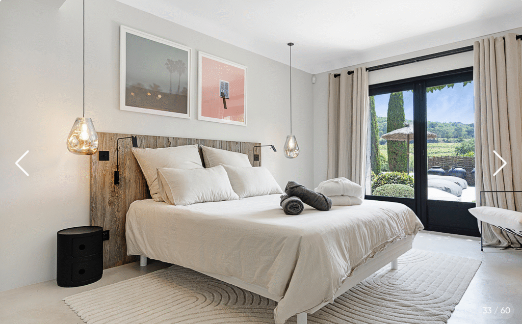 Grande chambre avec tête de lit en bois brut et linge de maison clair