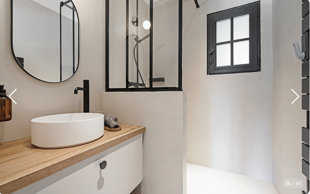 Salle de bain avec miroir rond, vasque design et douche en métal noir