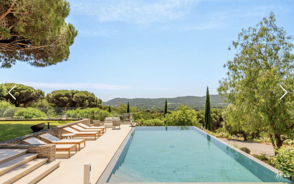 Piscine à débordement entourée de verdure avec transats et vue panoramique sur les collines de Saint-Raphaël