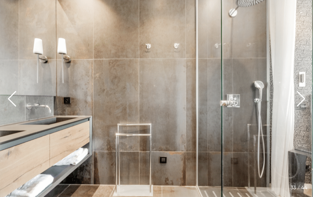 Salle de bain contemporaine avec éléments en bois clair, douche à l'italienne et rangement mural